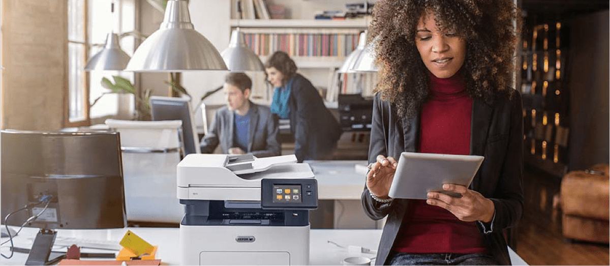 Femme afro travaillant sur tablette avec imprimante Xerox dans bureau