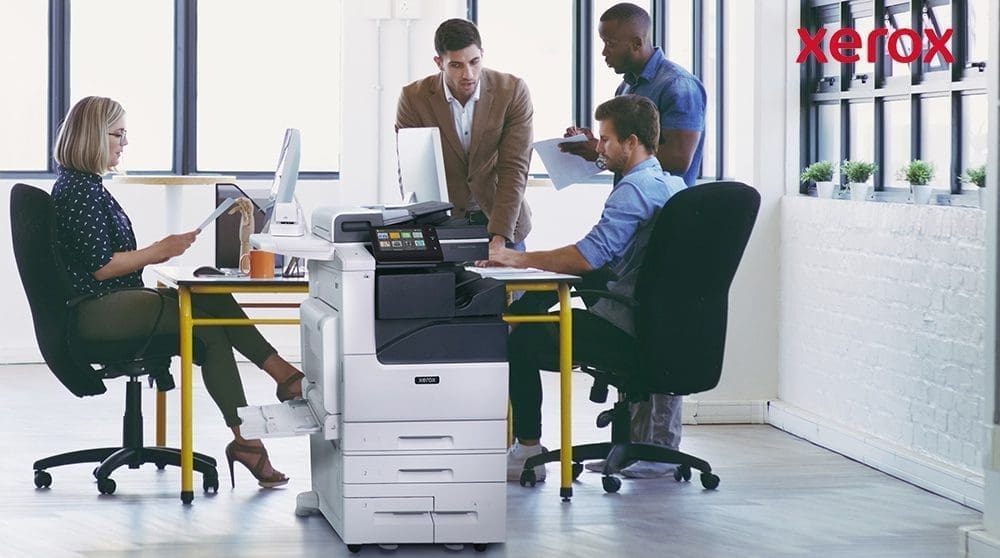 Employ&eacute;s de bureau collaborant &agrave; proximit&eacute; d'une imprimante Xerox.